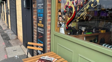 Exterior of Bell St. Barbers with vintage sign and outdoor seating in North Shields, England, GB.