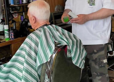 Barber gives haircut to customer at Bell St. Barbers, North Shields, England, GB.