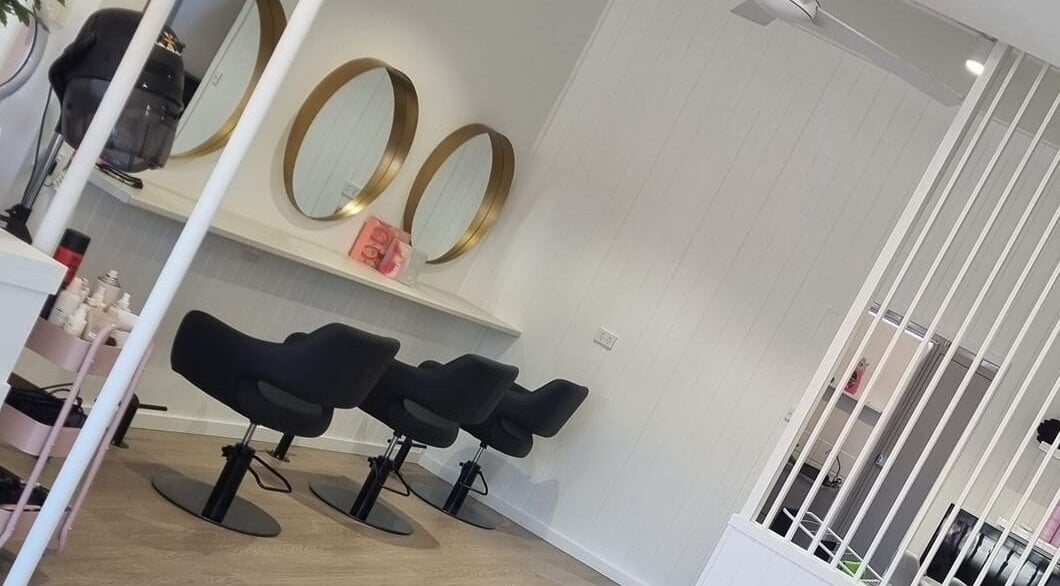 Stylish salon interior at Dalia Marie Hair, Fulham, South Australia, AU featuring sleek black chairs and gold mirrors.