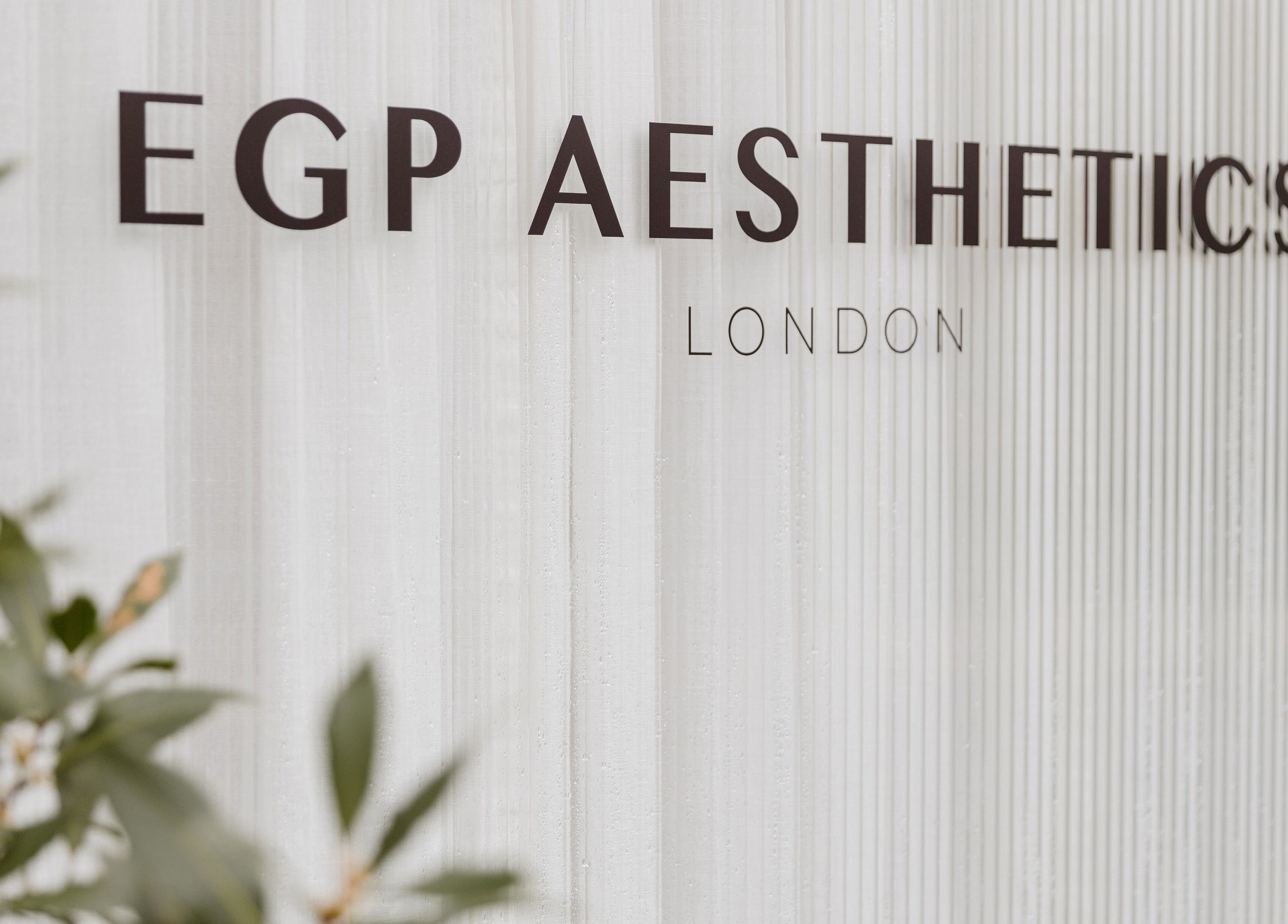 Signage of EGP Aesthetics in London, England, GB on a textured background with foliage.
