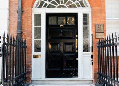 Front view of Barbanente Clinic entrance in London, England, GB with black door and iron fence.