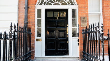 Front view of Barbanente Clinic entrance in London, England, GB with black door and iron fence.