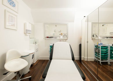 Treatment room at Barbanente Clinic in London, England. Reflective mirrors and cozy chair enhance calm atmosphere.