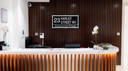 Elegant reception area at Barbanente Clinic, London, England, GB with wood paneling and marble desk.