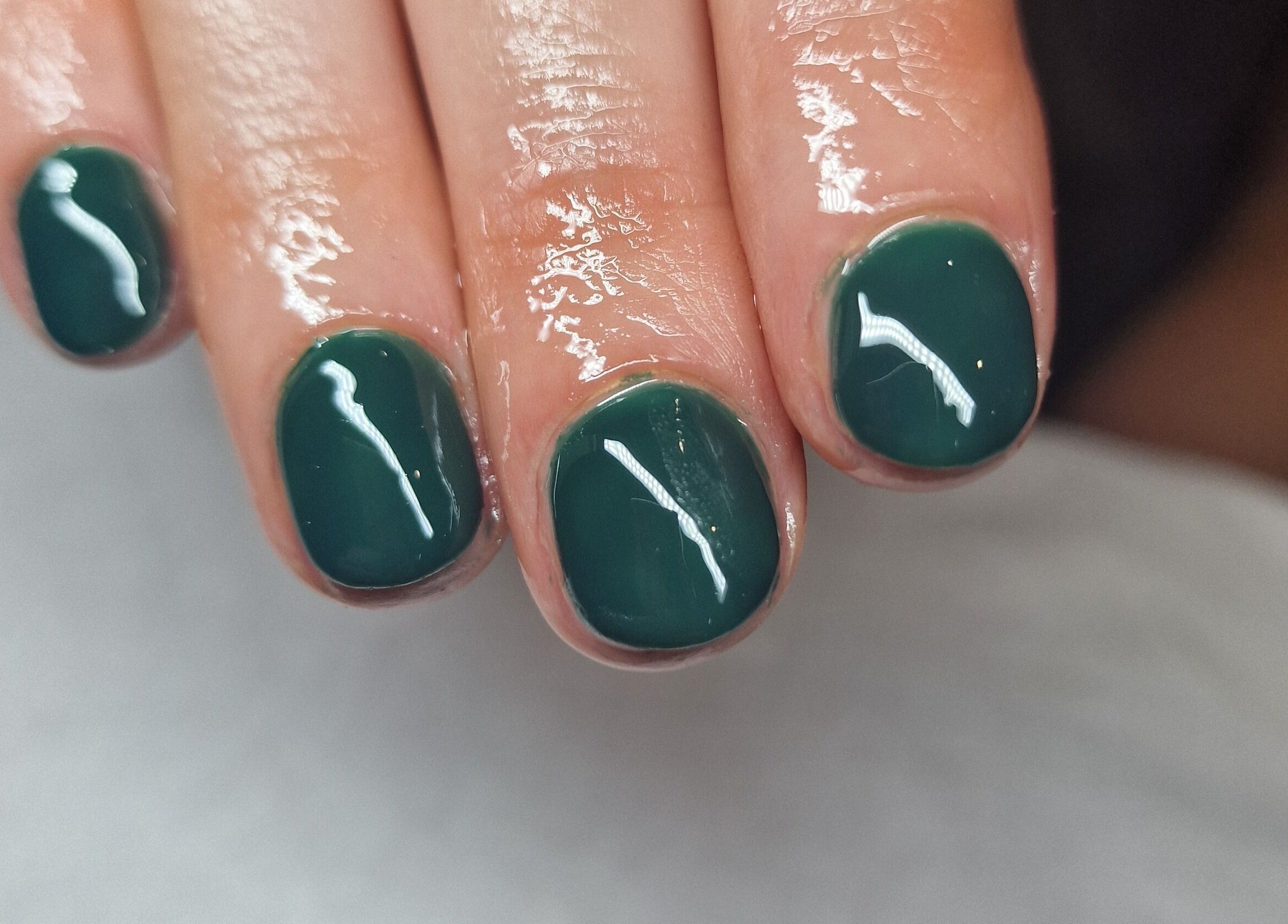 Close-up of glossy emerald green nails at Adore Beauty, Aberdeen, Scotland, GB.