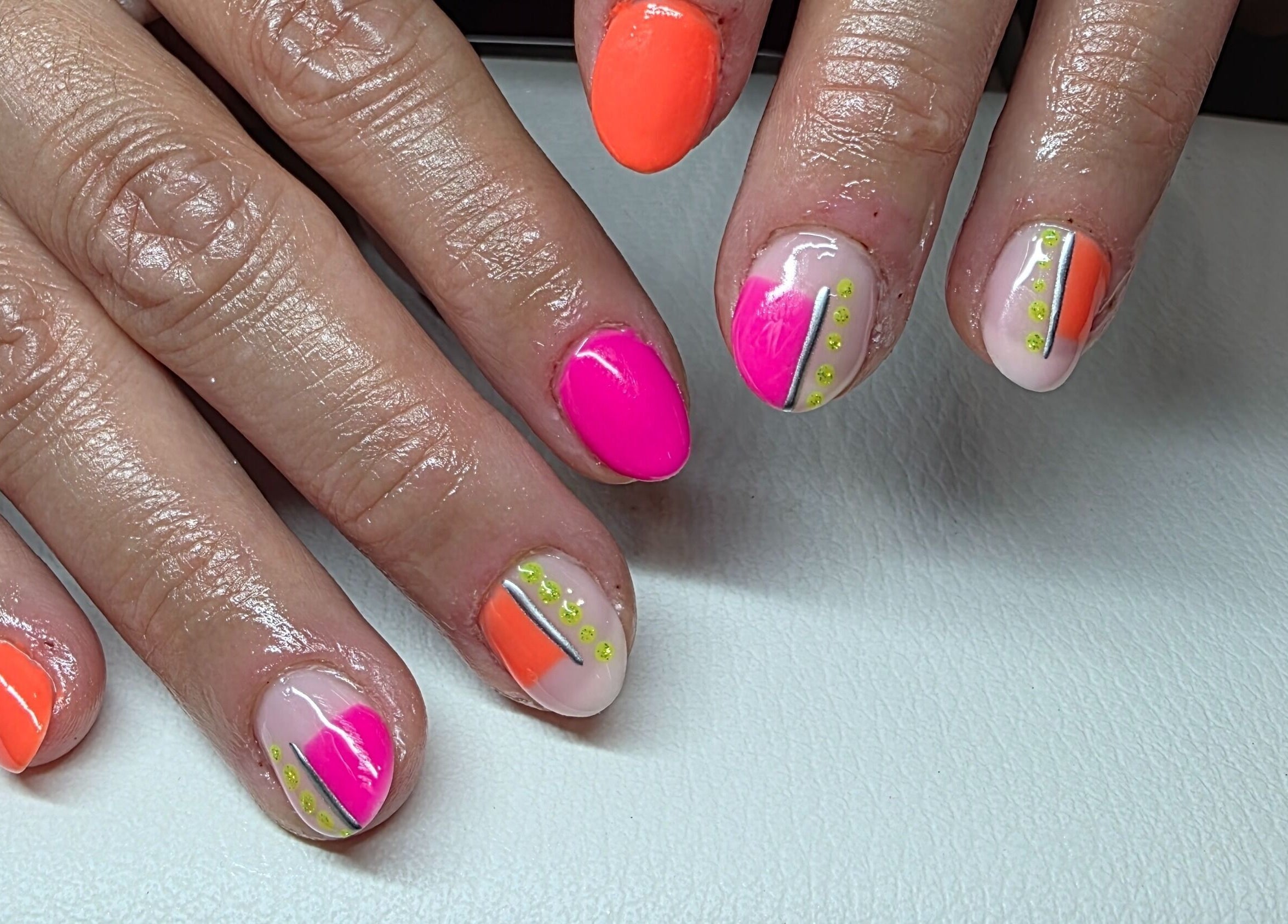 Colorful nail art featuring pink and orange designs at Adore Beauty, Aberdeen, Scotland, GB.