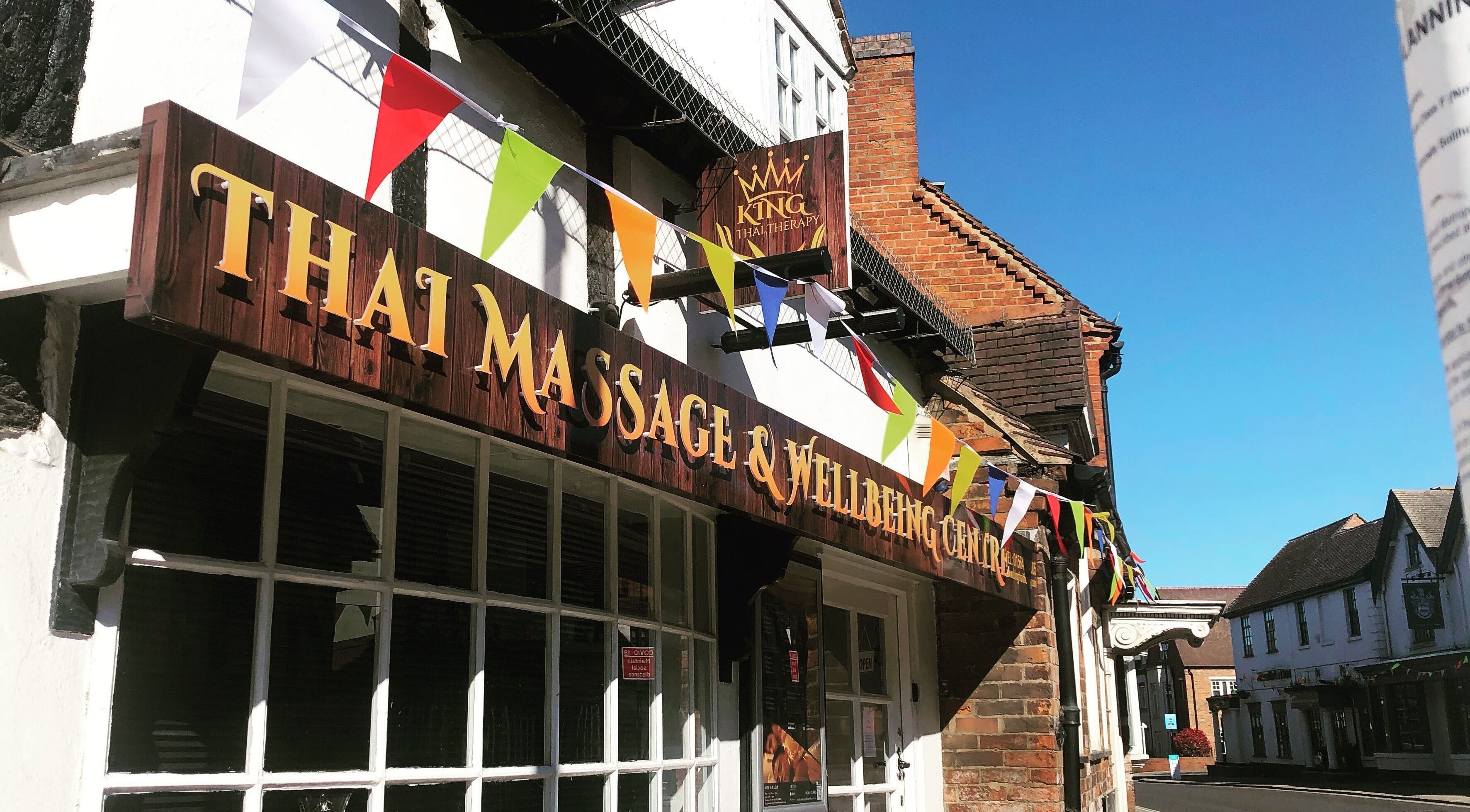 Entrance of King Thai Therapy Knowle in Knowle, England, GB, decorated with colorful flags.