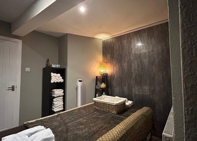 Cozy massage room at King Thai Therapy Knowle, Knowle, England, GB with soft lighting and neatly arranged towels.