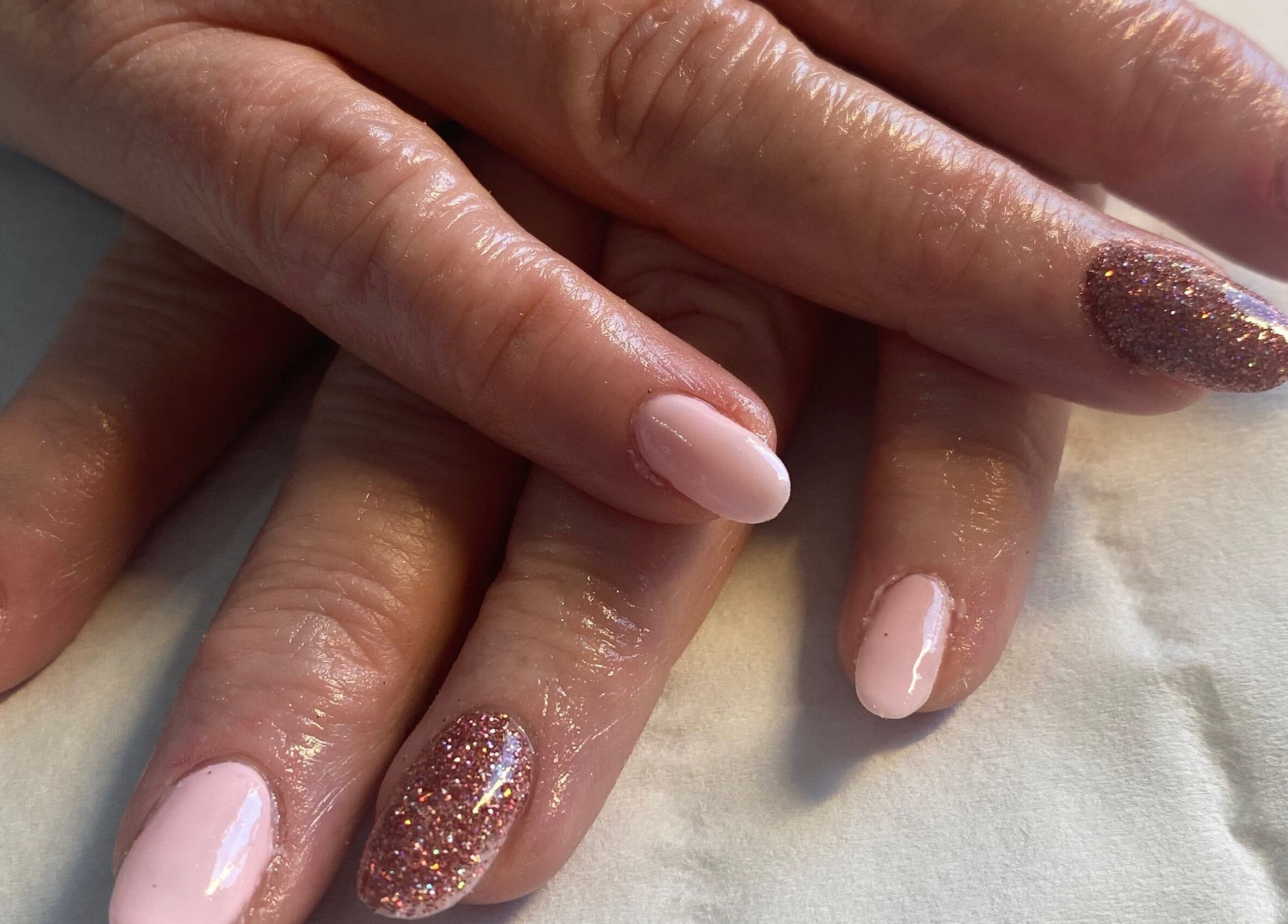 Pink and glitter nails at Beauty and Beyond, Greenock, Scotland, GB. Perfectly manicured hands displayed elegantly.
