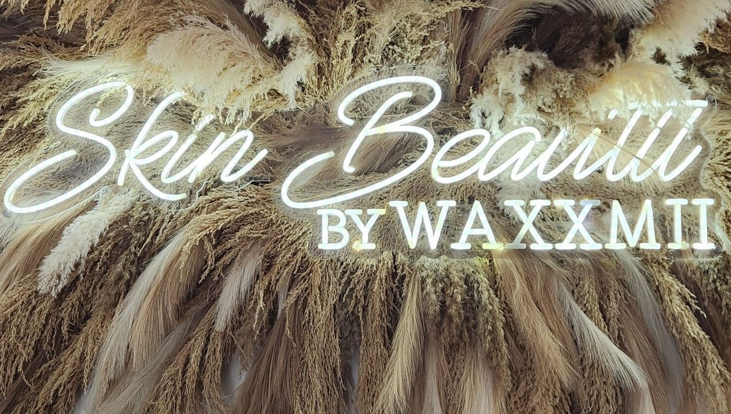 Illuminated Skin Beautii by Robinson Rd sign with pampas grass in Nassau, New Providence, BS.