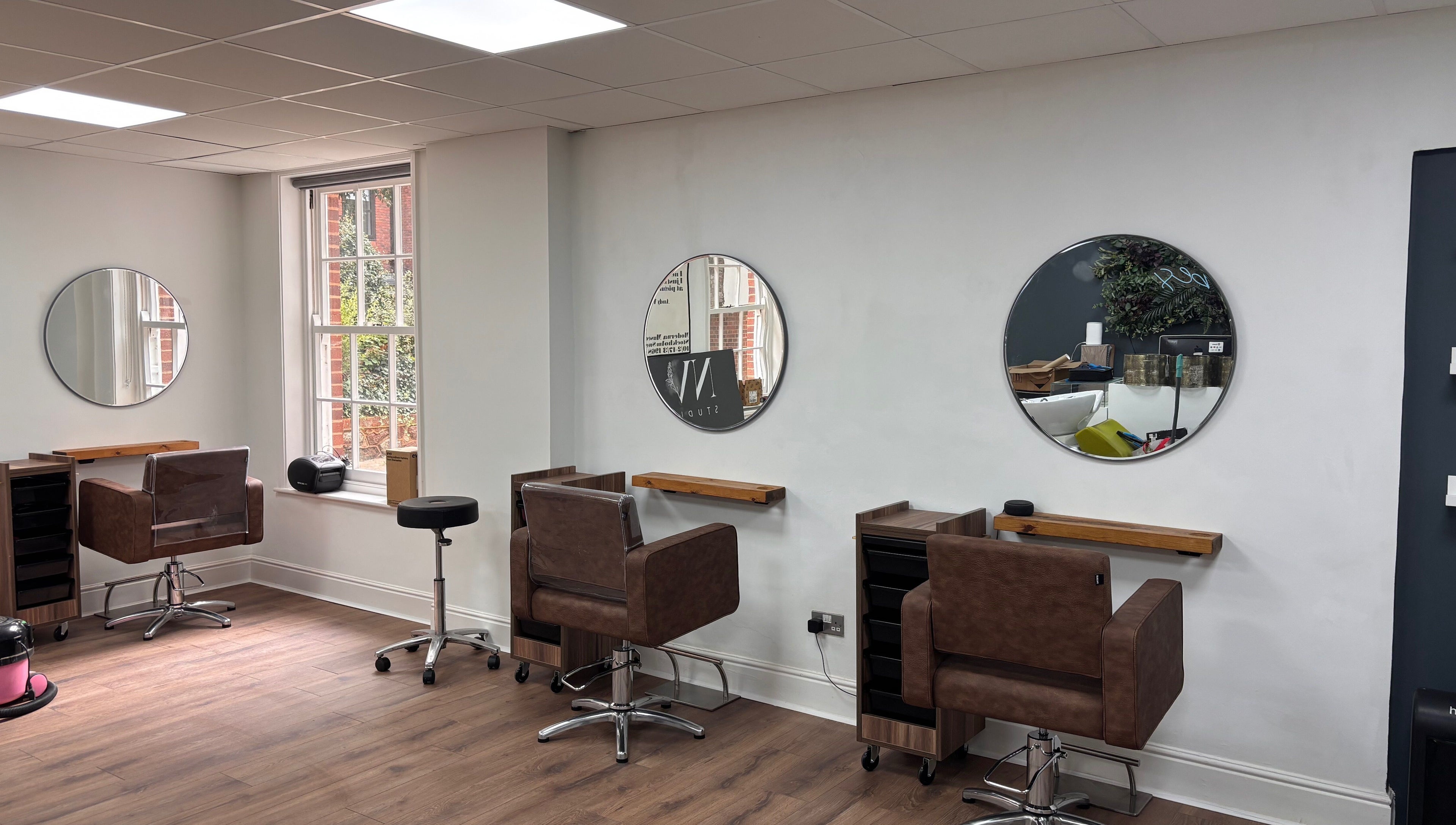 Sophisticated salon seating at Nv Studio, Exeter, England, GB, featuring modern mirrors and stylish chairs.