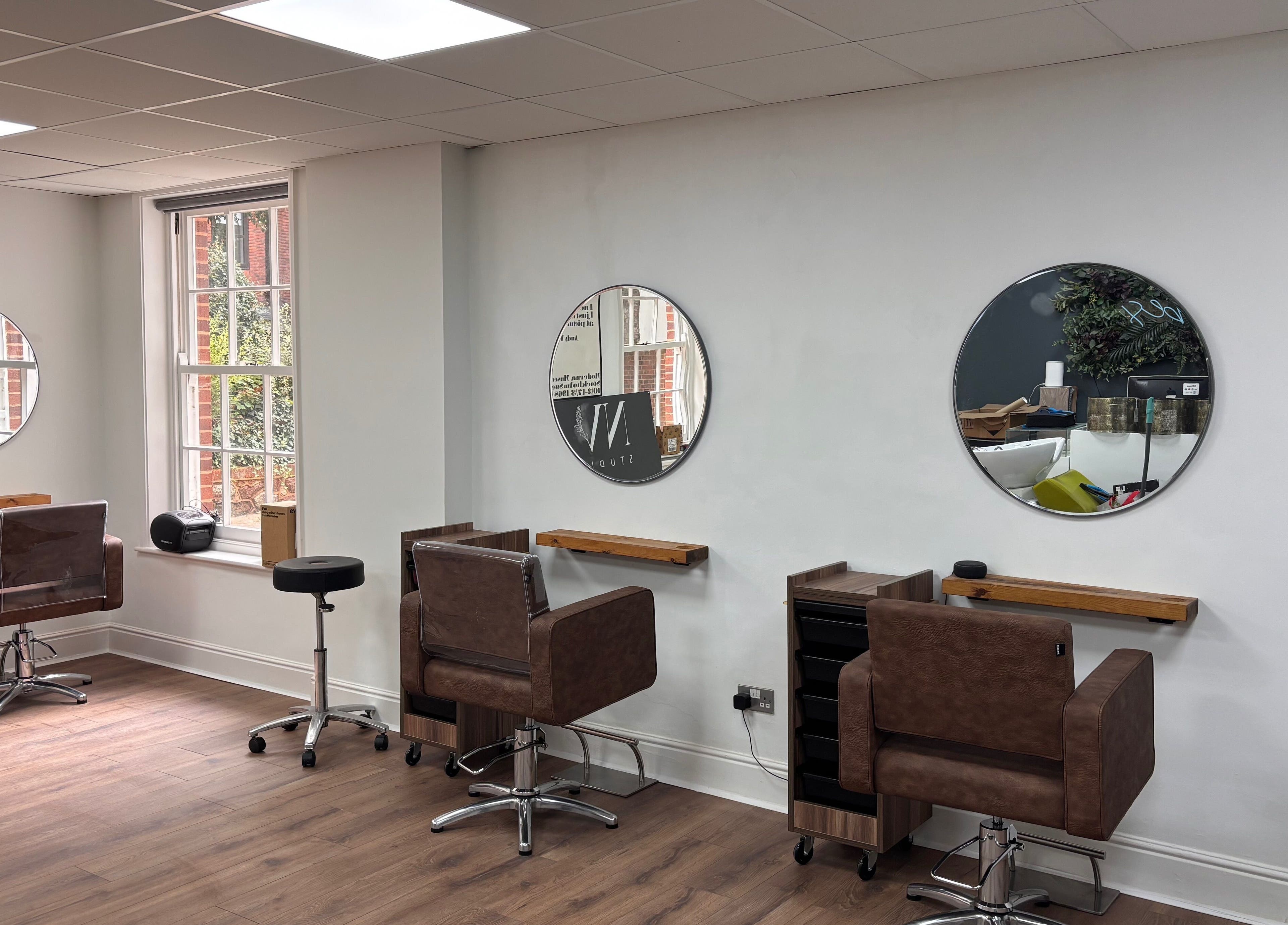 Sophisticated salon seating at Nv Studio, Exeter, England, GB, featuring modern mirrors and stylish chairs.