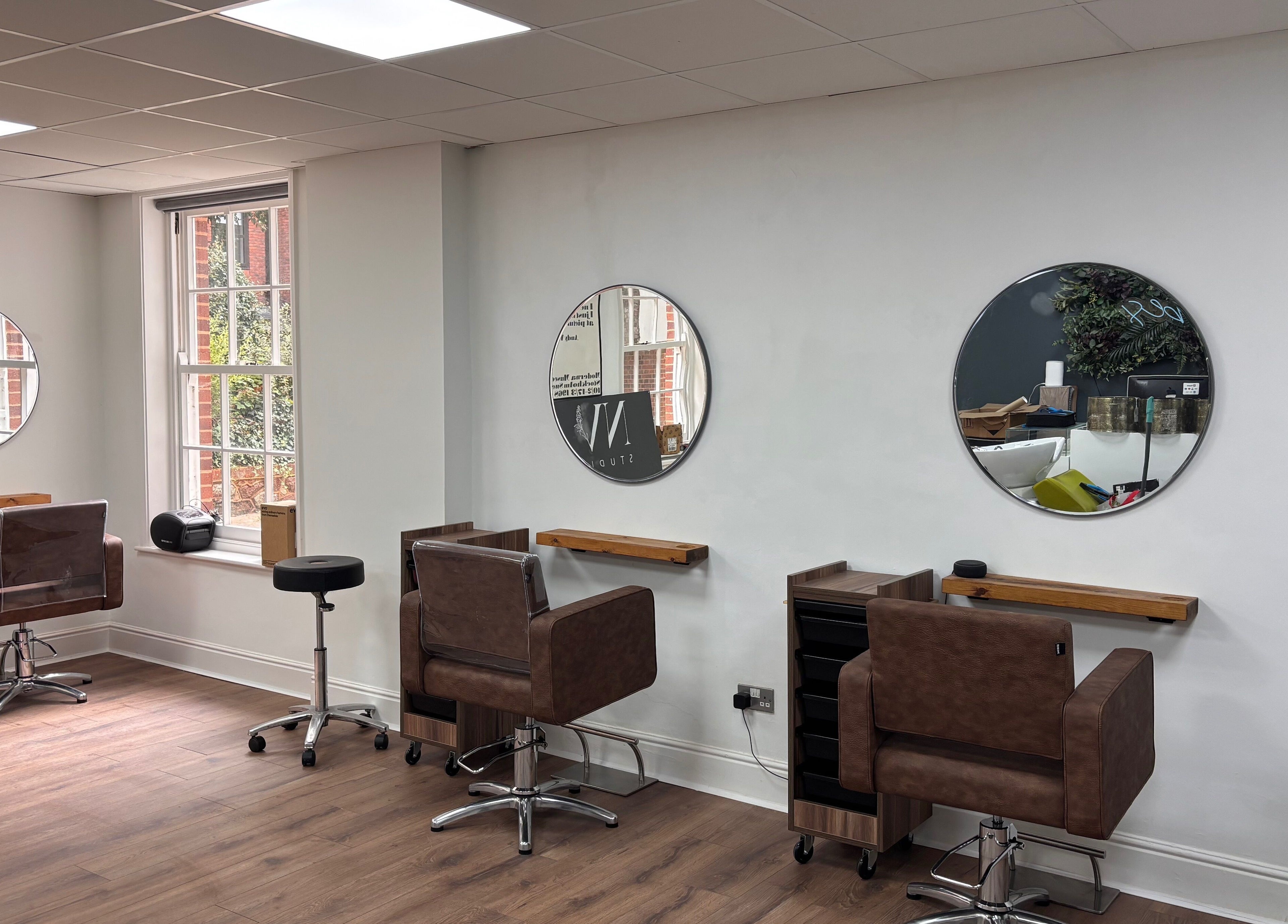 Sophisticated salon seating at Nv Studio, Exeter, England, GB, featuring modern mirrors and stylish chairs.
