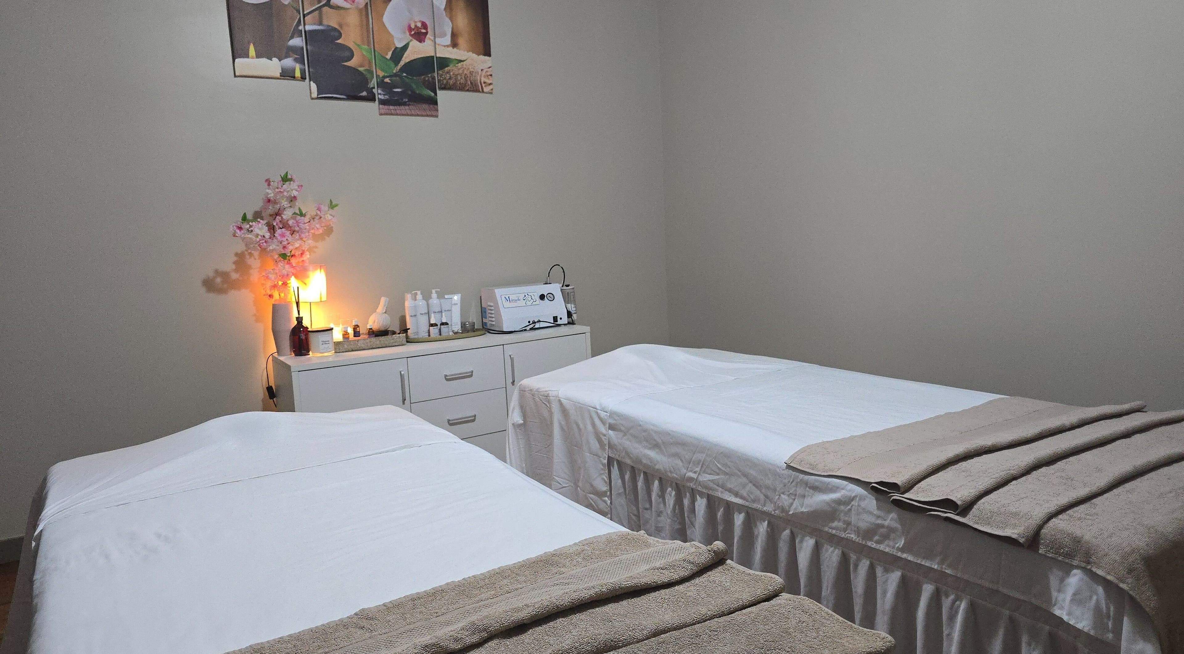 Relaxing massage room at Natara Spa & Massage, Auckland, NZ with two beds, warm lighting, and elegant decor.