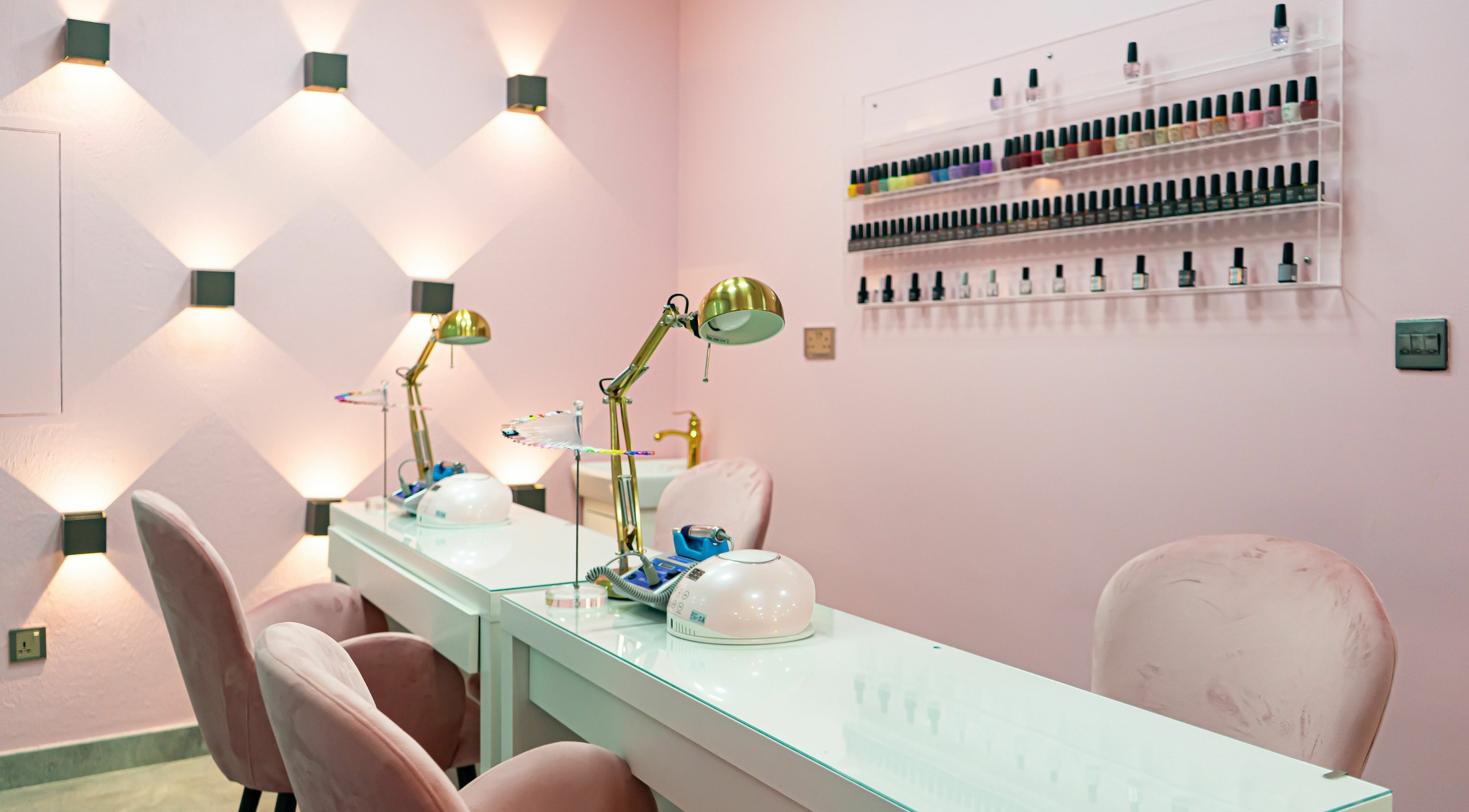Modern nail lounge at Afroglam Beauty Salon, Dubai, AE with elegant pink decor and nail polish display.