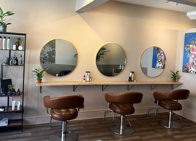Modern salon interior at Forté in Louth, England, GB, featuring stylish brown chairs and circular mirrors.