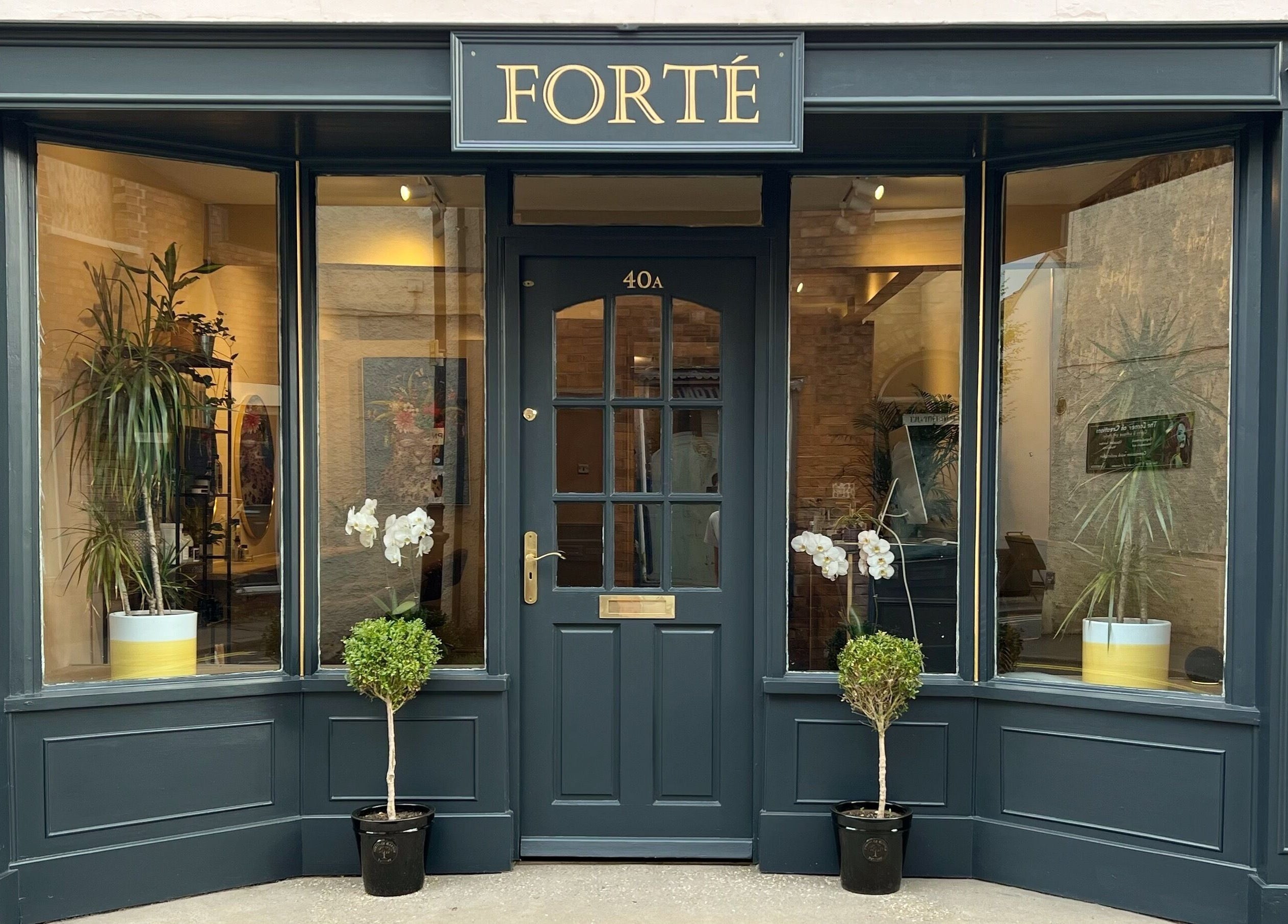 Entrance of Forté beauty venue in Louth, England, GB with stylish dark frames and greenery.