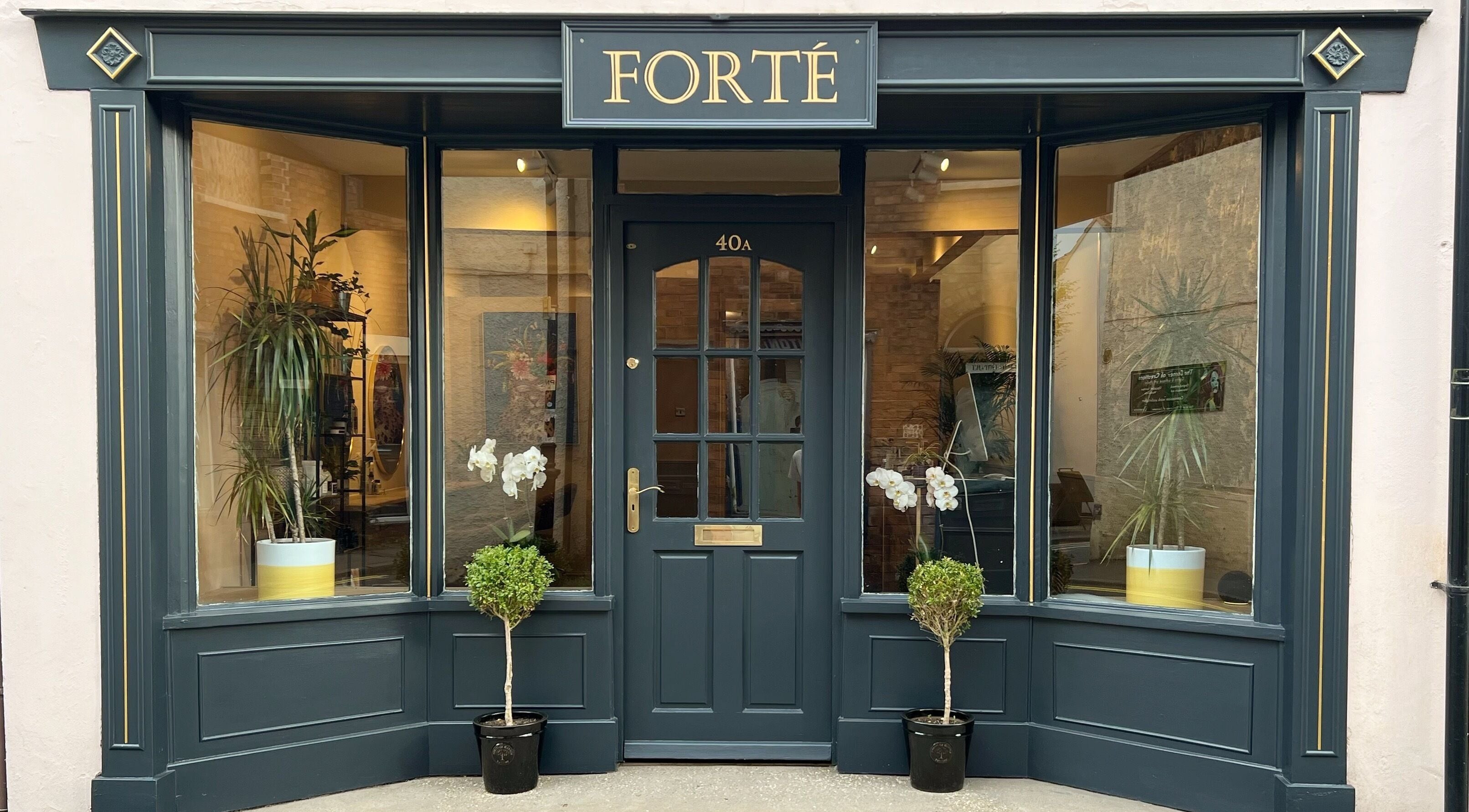 Entrance of Forté beauty venue in Louth, England, GB with stylish dark frames and greenery.