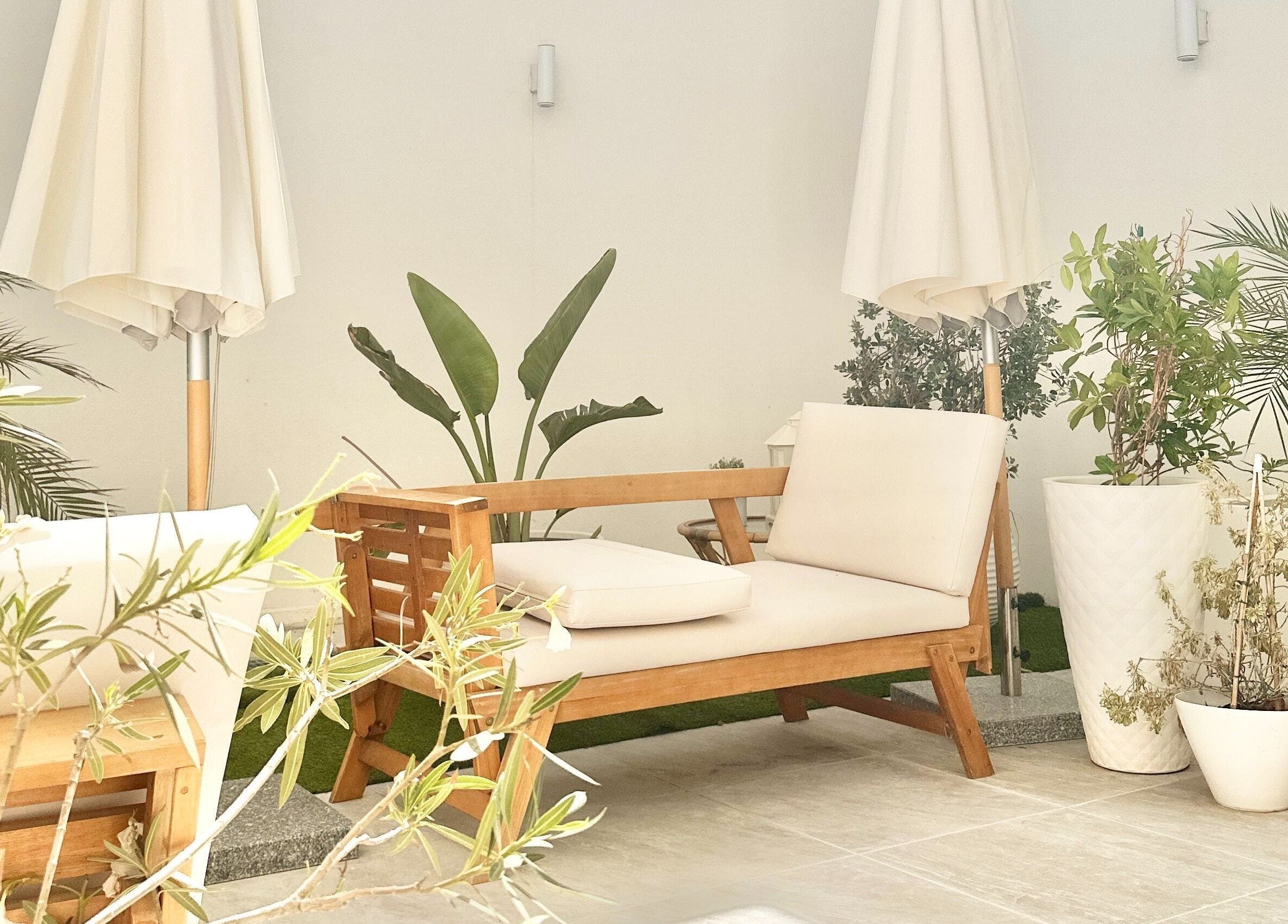 Relaxing outdoor seating at Fountain of Youth, Ħal Balzan, MT, surrounded by lush greenery and white umbrellas.
