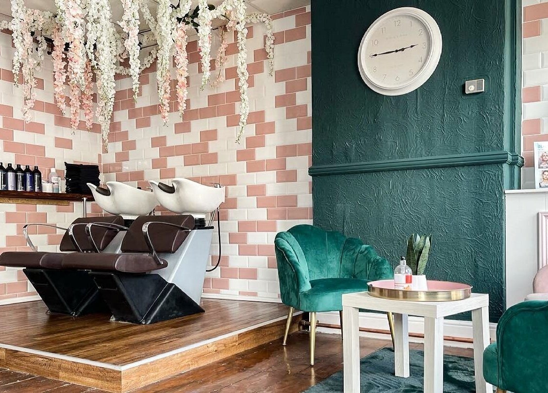 Stylish interior at MK Salon, Lowestoft, England with floral decor and green chairs near washing stations.