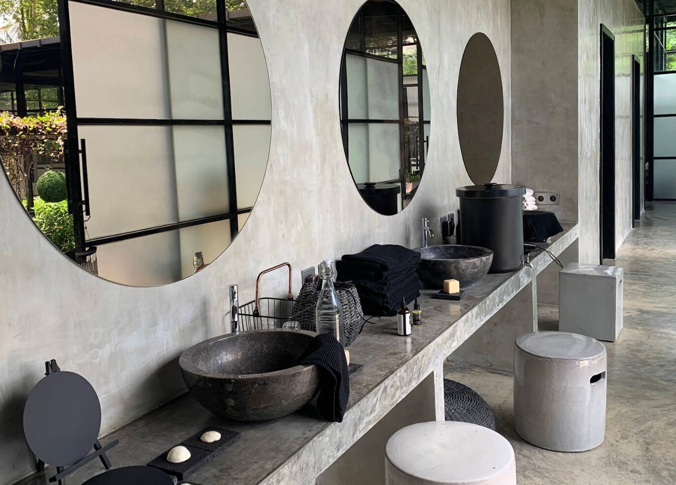 Elegant vanity area at Muka Concepts Jalan Green School, Sibang Kaja, Bali, ID, with round mirrors and stone sinks.