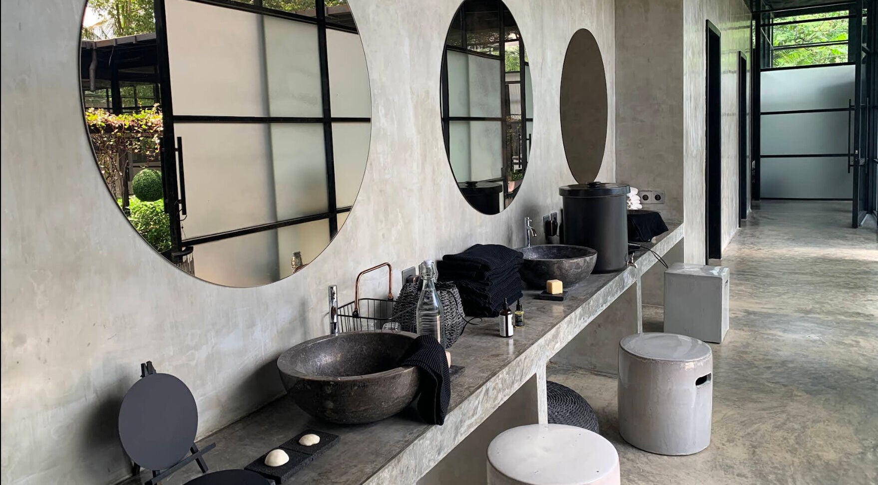 Elegant vanity area at Muka Concepts Jalan Green School, Sibang Kaja, Bali, ID, with round mirrors and stone sinks.