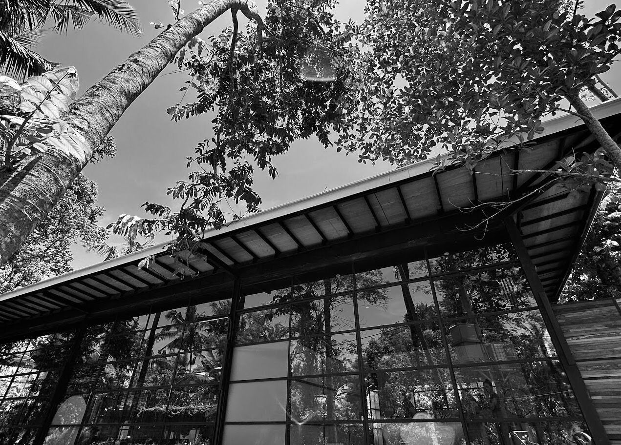 Muka Concepts Jalan Green School's glass facade amidst lush greenery in Sibang Kaja, Bali, ID.