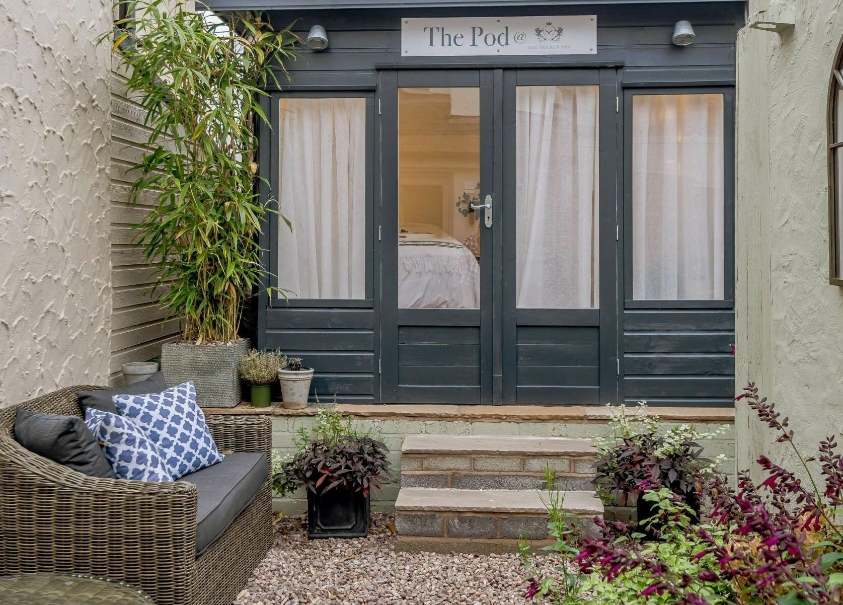 Charming entrance to The Secret Spa's Pod in Holt, Wales, GB, surrounded by lush plants and elegant decor.