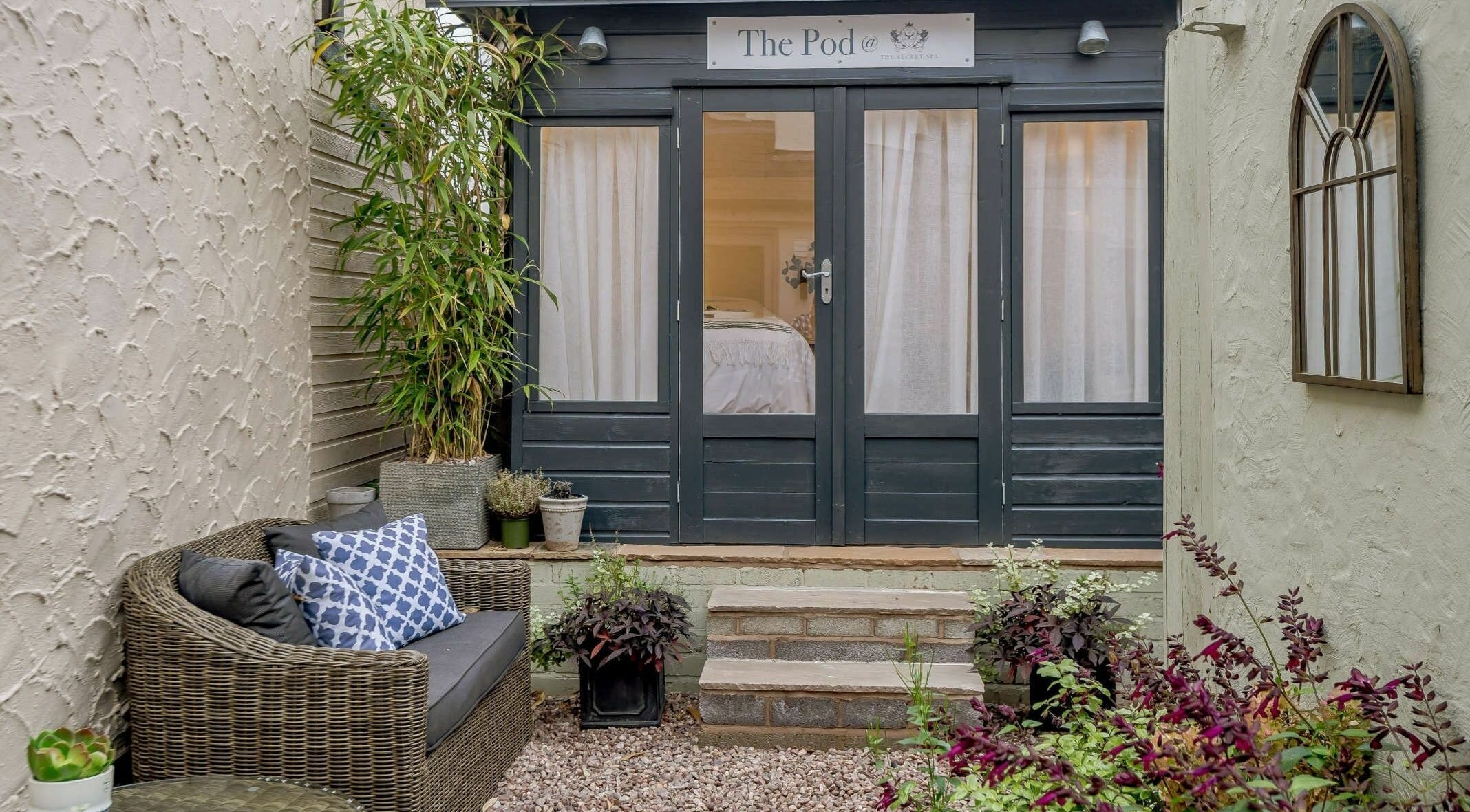 Charming entrance to The Secret Spa's Pod in Holt, Wales, GB, surrounded by lush plants and elegant decor.