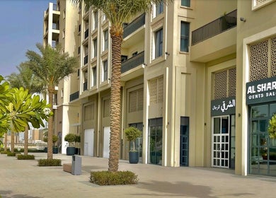 Front view of Sharqi Gents Salon in Sharjah, AE, featuring palm trees and modern architecture.