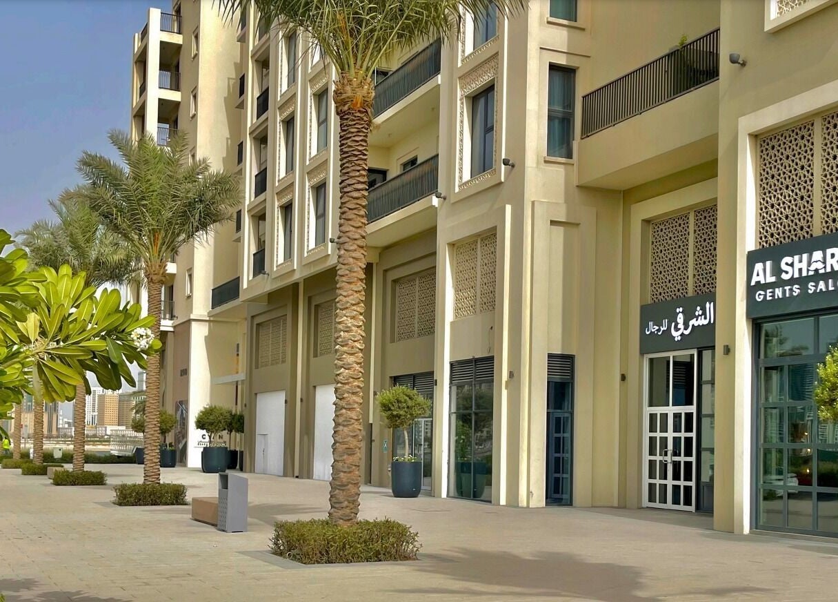 Front view of Sharqi Gents Salon in Sharjah, AE, featuring palm trees and modern architecture.