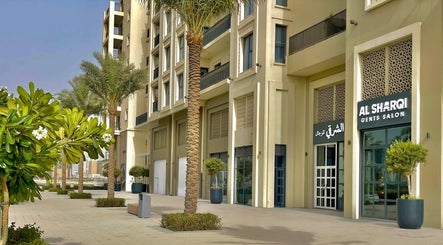 Front view of Sharqi Gents Salon in Sharjah, AE, featuring palm trees and modern architecture.