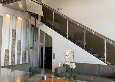 Elegante interior de Novalaser en San Rafael, San José, CR con escalera moderna y sofá gris.