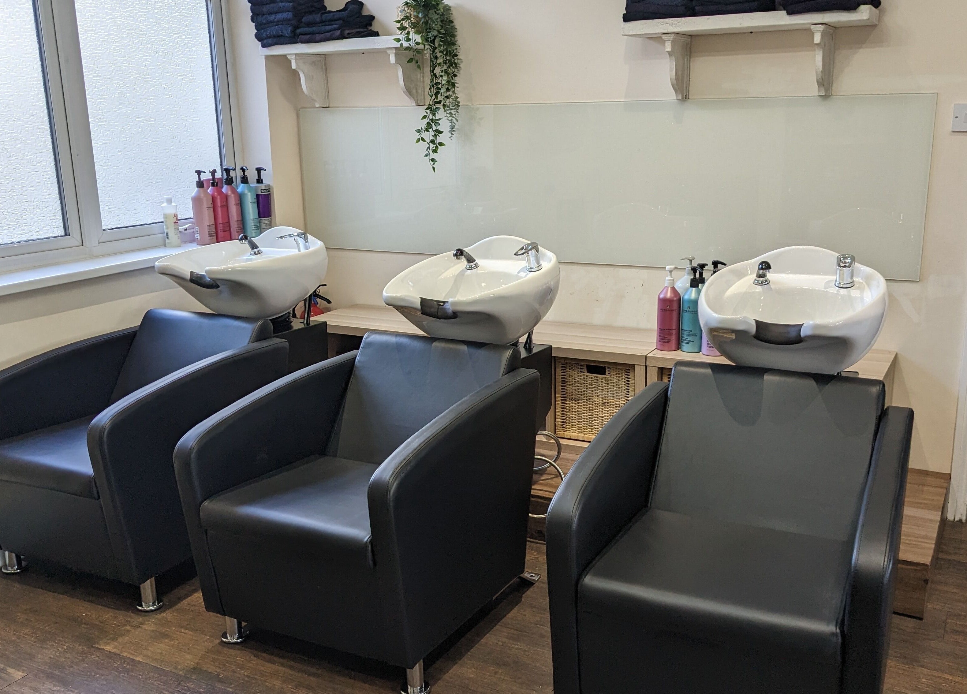 Modern wash stations at No.77 Hair Salon Coulsdon, Coulsdon, England, GB. Stylish black chairs and sinks.