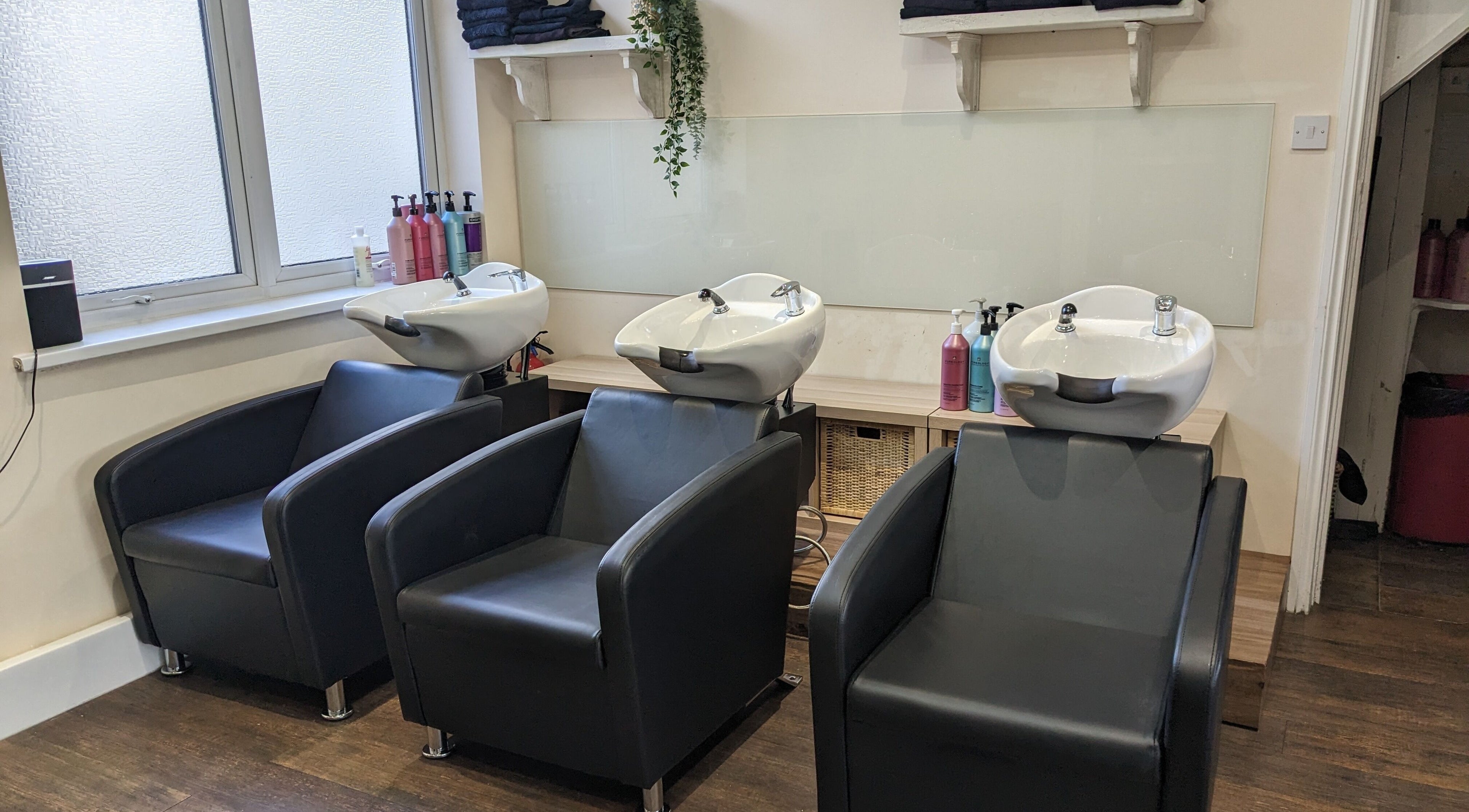Modern wash stations at No.77 Hair Salon Coulsdon, Coulsdon, England, GB. Stylish black chairs and sinks.