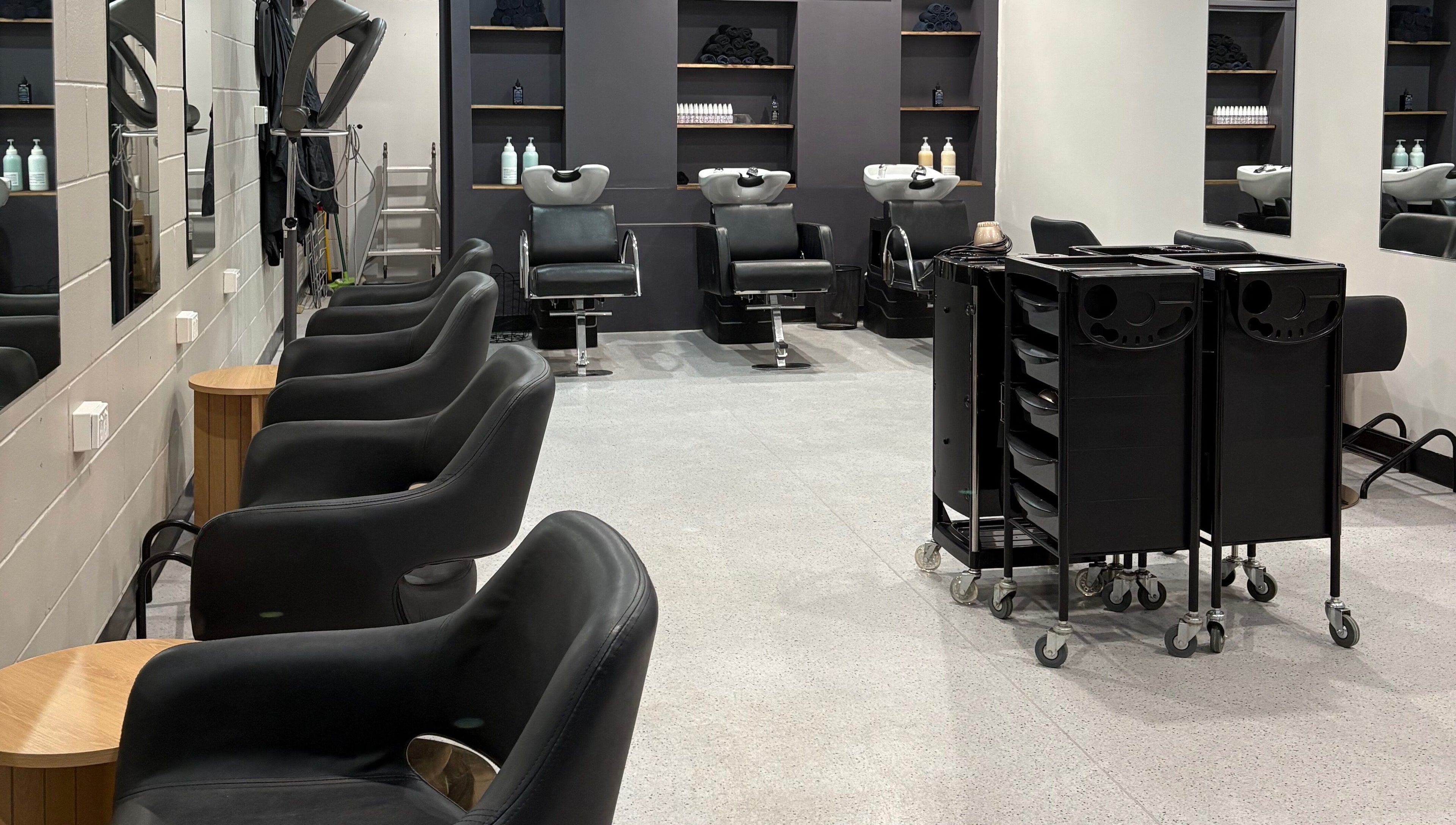 Sleek salon interior with black chairs at The Hair Collective - Arana Hills, Arana Hills, Queensland, AU.