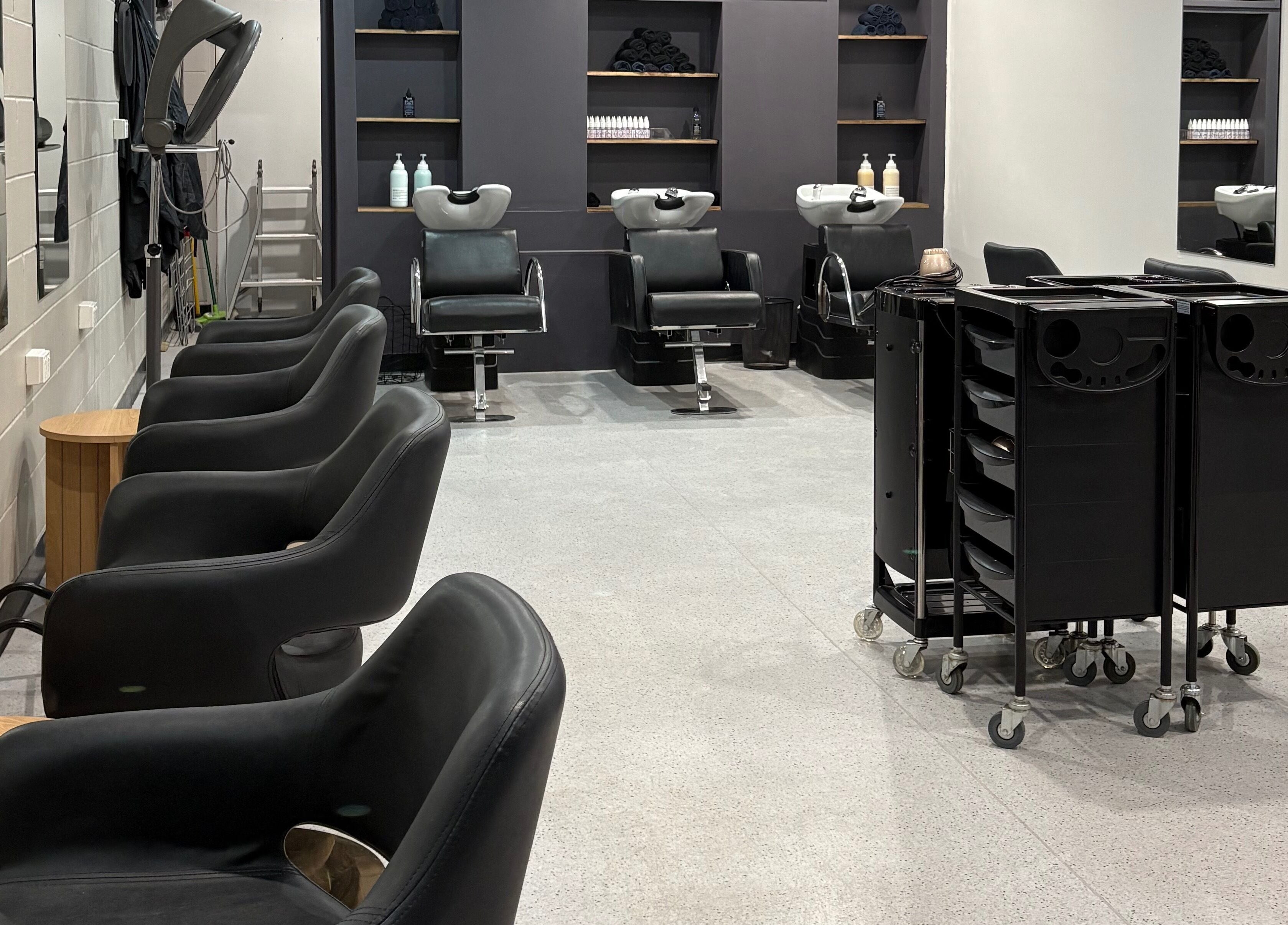 Sleek salon interior with black chairs at The Hair Collective - Arana Hills, Arana Hills, Queensland, AU.
