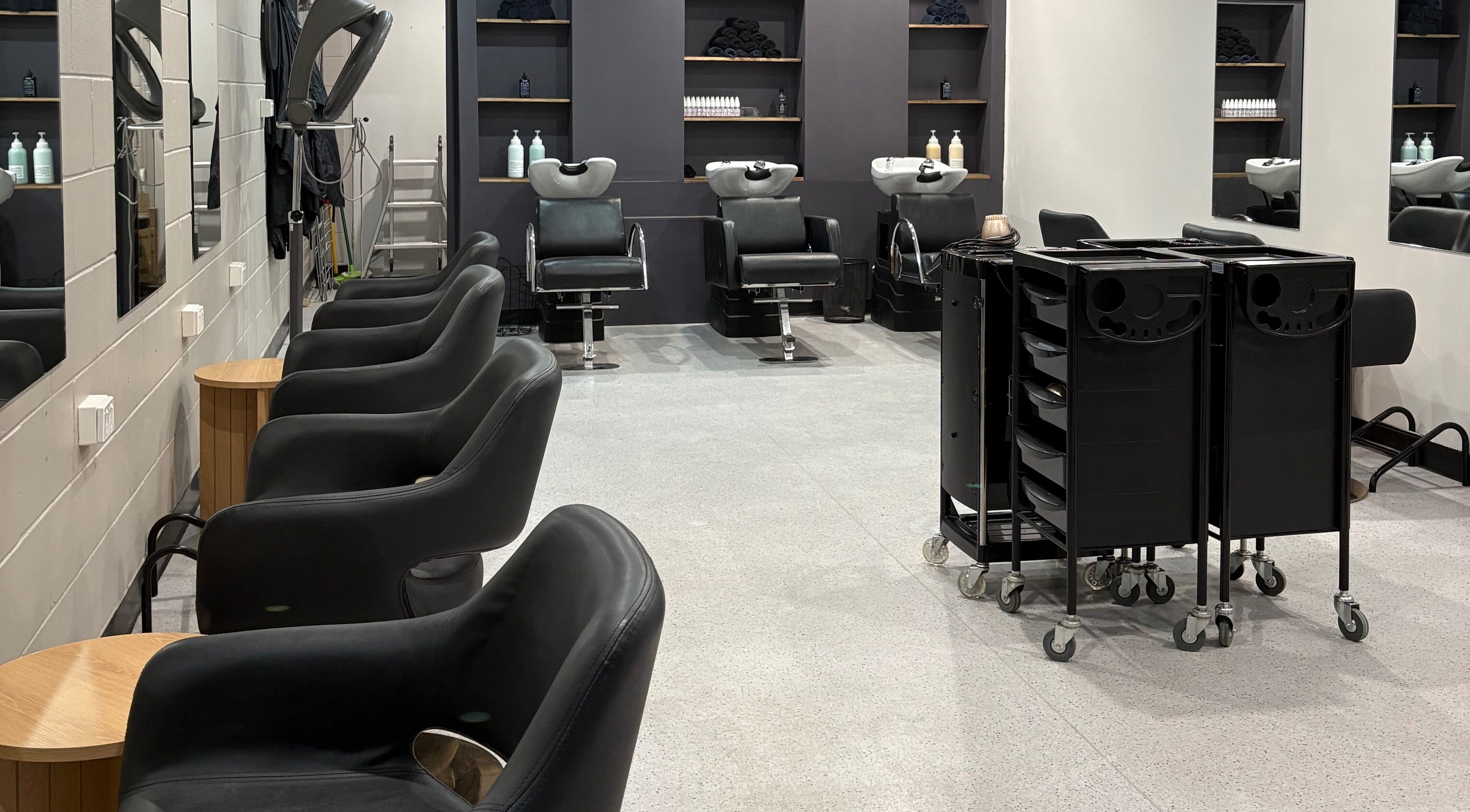 Sleek salon interior with black chairs at The Hair Collective - Arana Hills, Arana Hills, Queensland, AU.
