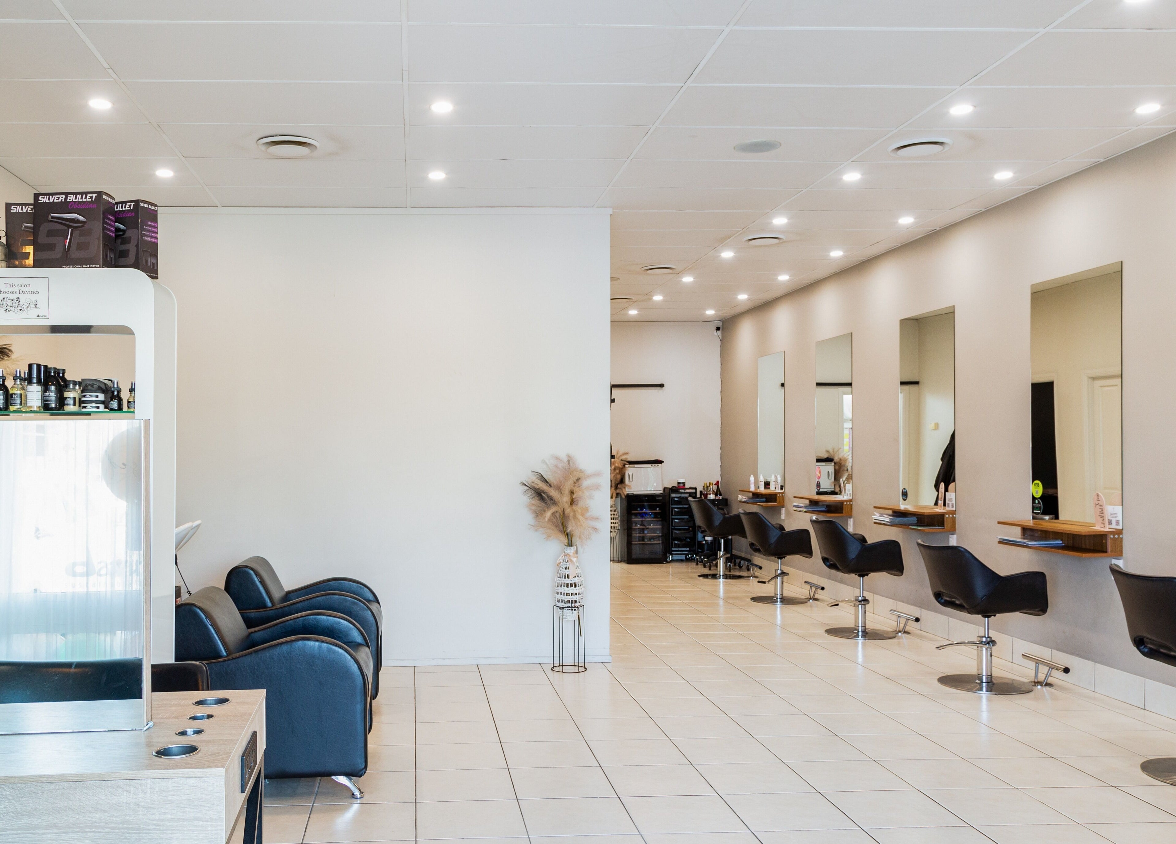 Modern salon at The Hair Collective - Aesthetics Co., Helensvale, Queensland, AU, with sleek chairs and stylish decor.