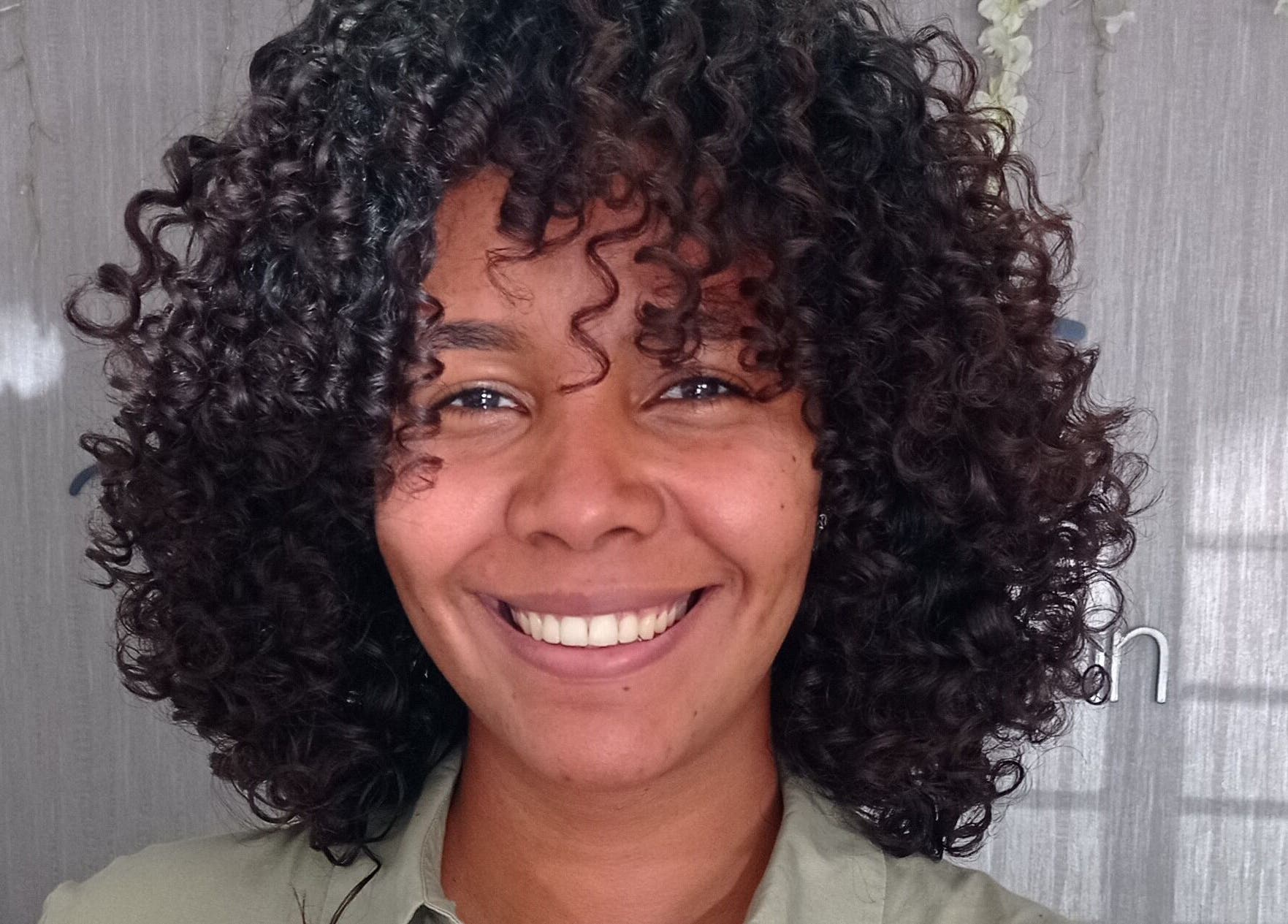 Cliente sonriente en Beauty Space by Jenn, San Pedro de Macoris, mostrando su cabello rizado y cuidado.