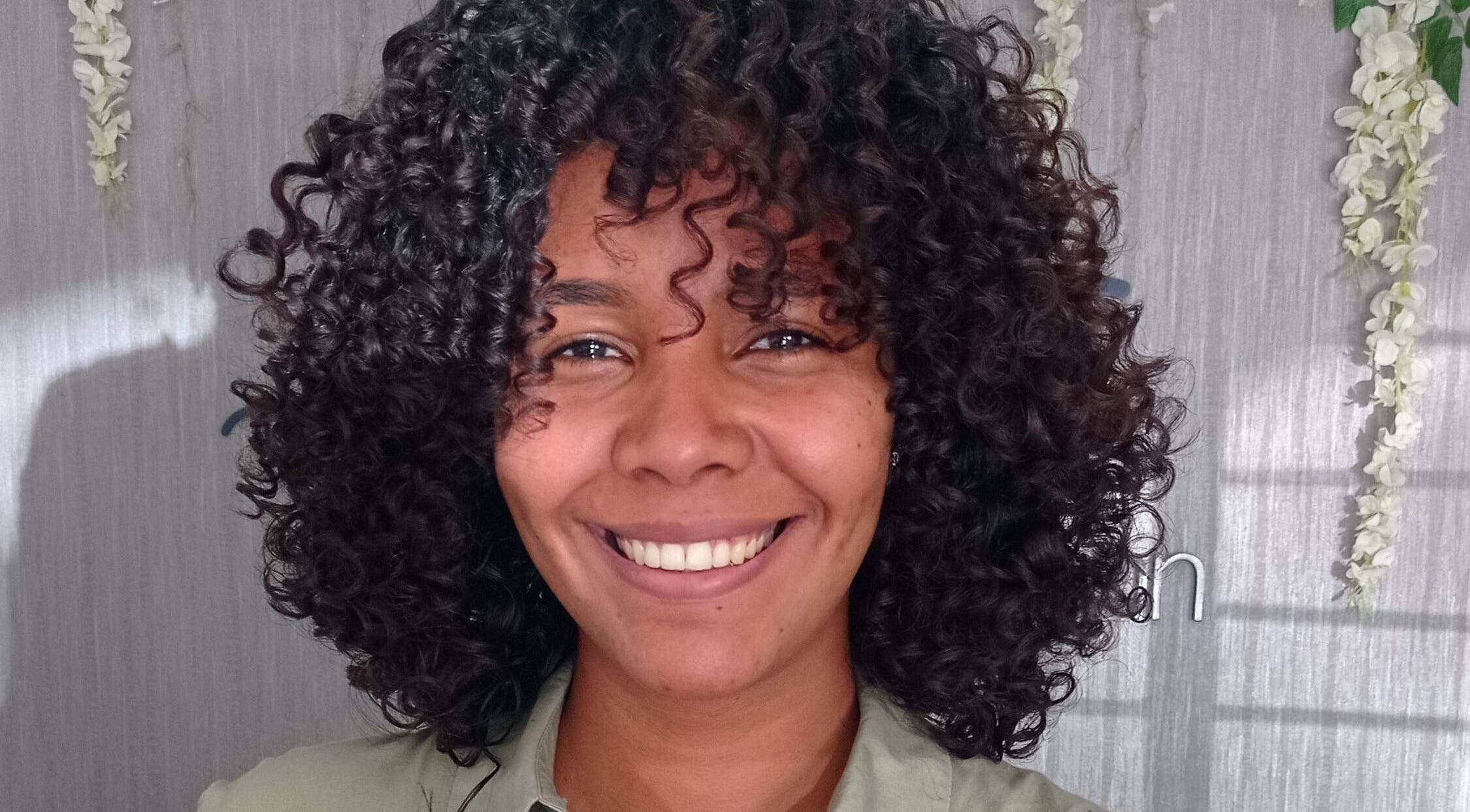 Cliente sonriente en Beauty Space by Jenn, San Pedro de Macoris, mostrando su cabello rizado y cuidado.