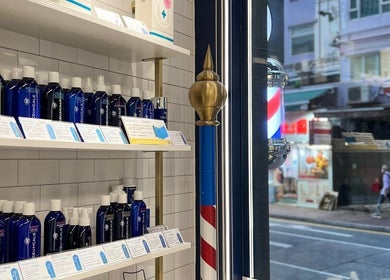 Shelf of hair products at Dudes Barbershop, Sheung Wan, Hong Kong Island, HK, with classic barber pole.