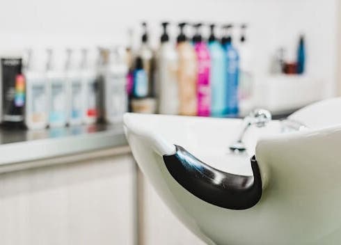 Elegantní umyvadlo v salonu IHair v Semily, Liberecký kraj, CZ s vlasovými produkty v pozadí.