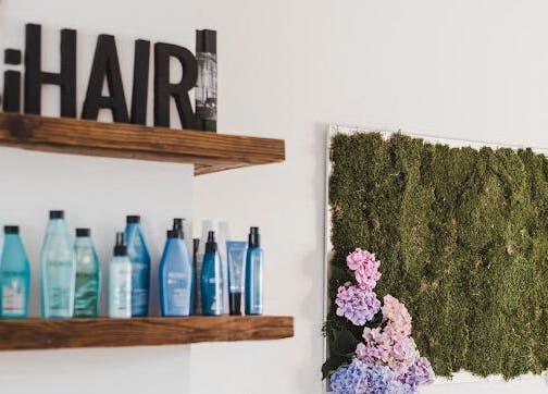 Interiér IHair v Semily, Liberecký kraj: police s kosmetikou a zelenou dekorací.