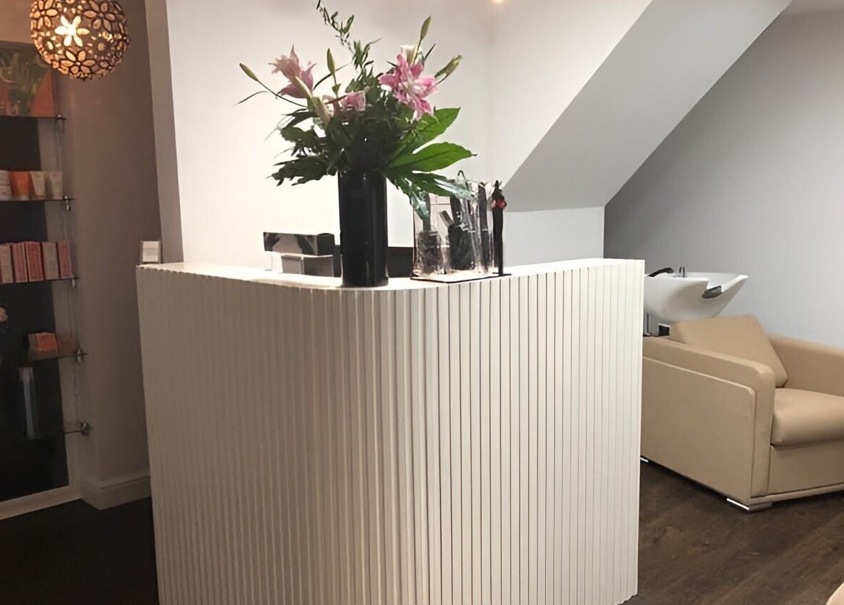 Reception area at The Salon Holt, featuring a stylish desk and plush seating in Holt, Wales, GB.