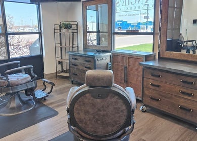 A cozy barber chair at Angie’s Barbershop, Billings, Montana, US, with rustic wooden decor and large windows.