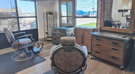 A cozy barber chair at Angie’s Barbershop, Billings, Montana, US, with rustic wooden decor and large windows.