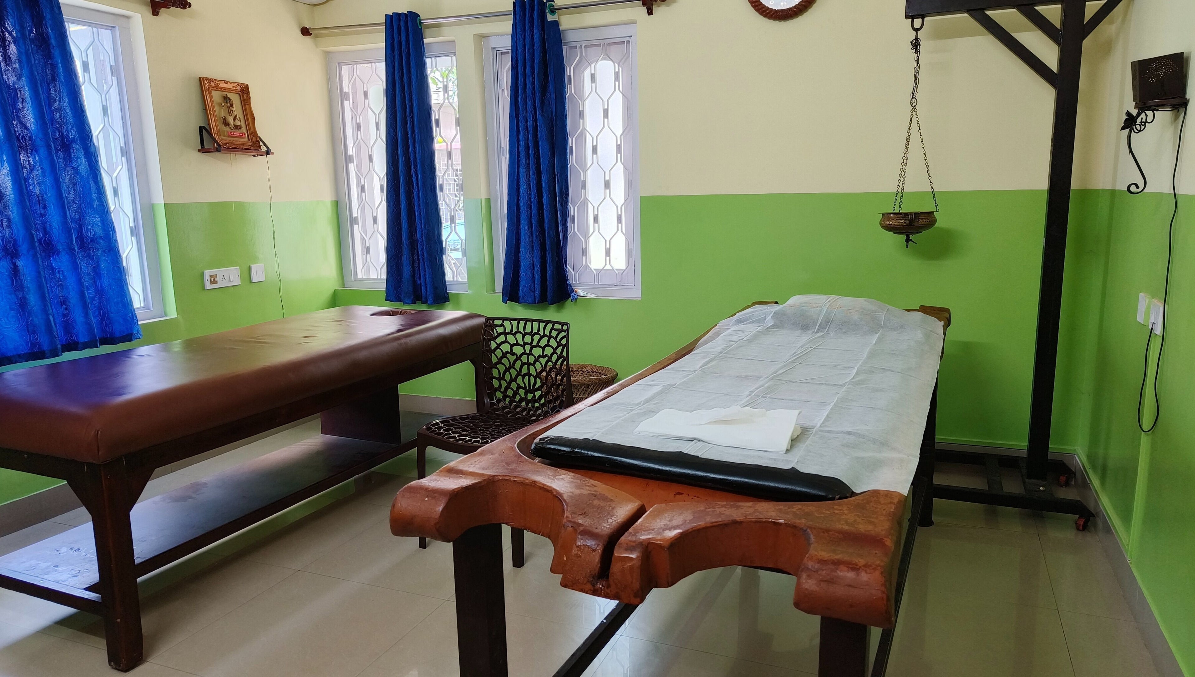 Therapy room at Arogya Ayurveda Panchakarma Center Pvt. Ltd. in Kolkata, West Bengal, IN with massage tables and decor.