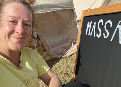 Expert at LZ Massage Therapies in Whitley Bay, England, smiles beside a massage sign outdoors.