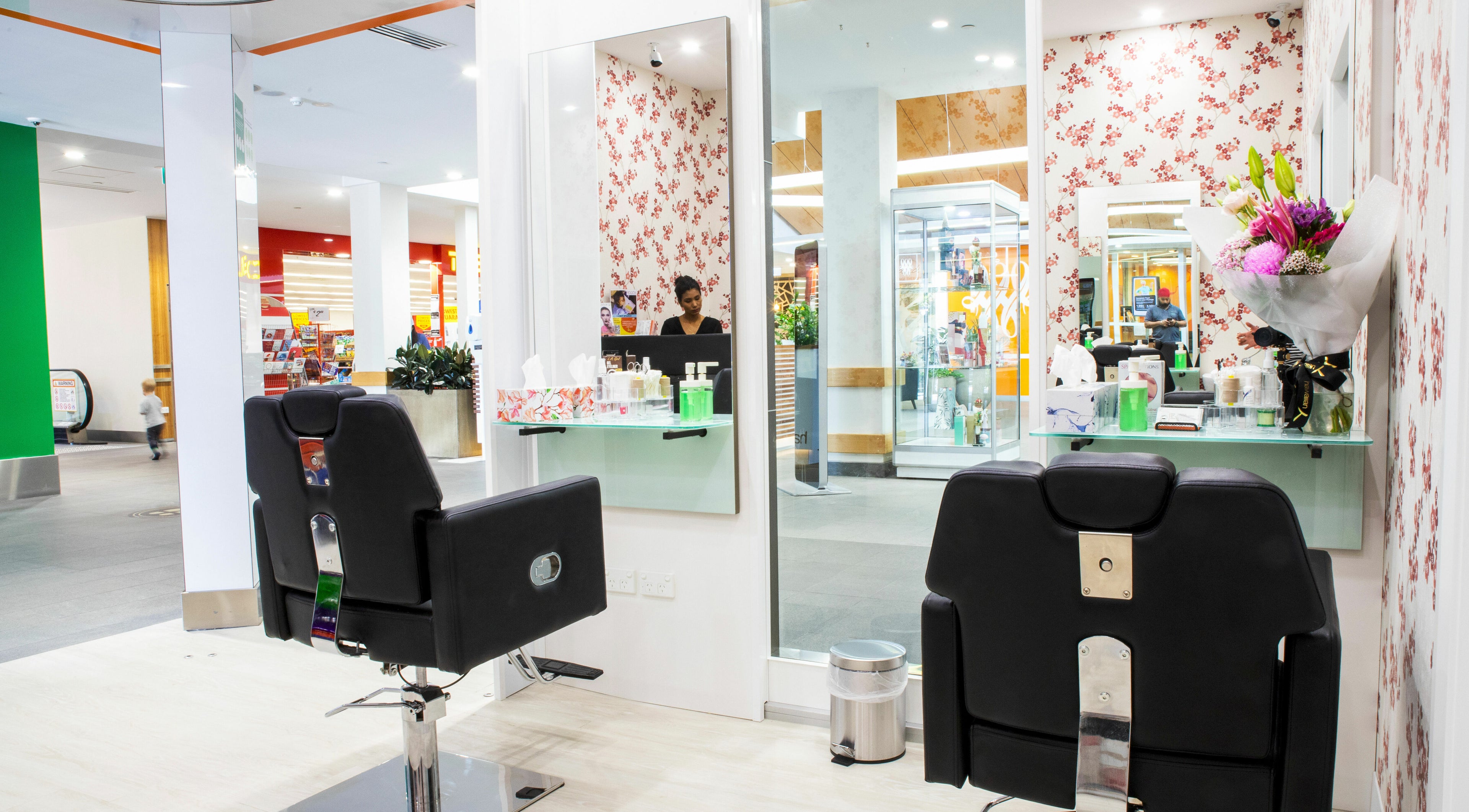 Modern salon interior at Manyas Bassendean, Bassendean, WA, AU, featuring stylish black chairs and floral decor.